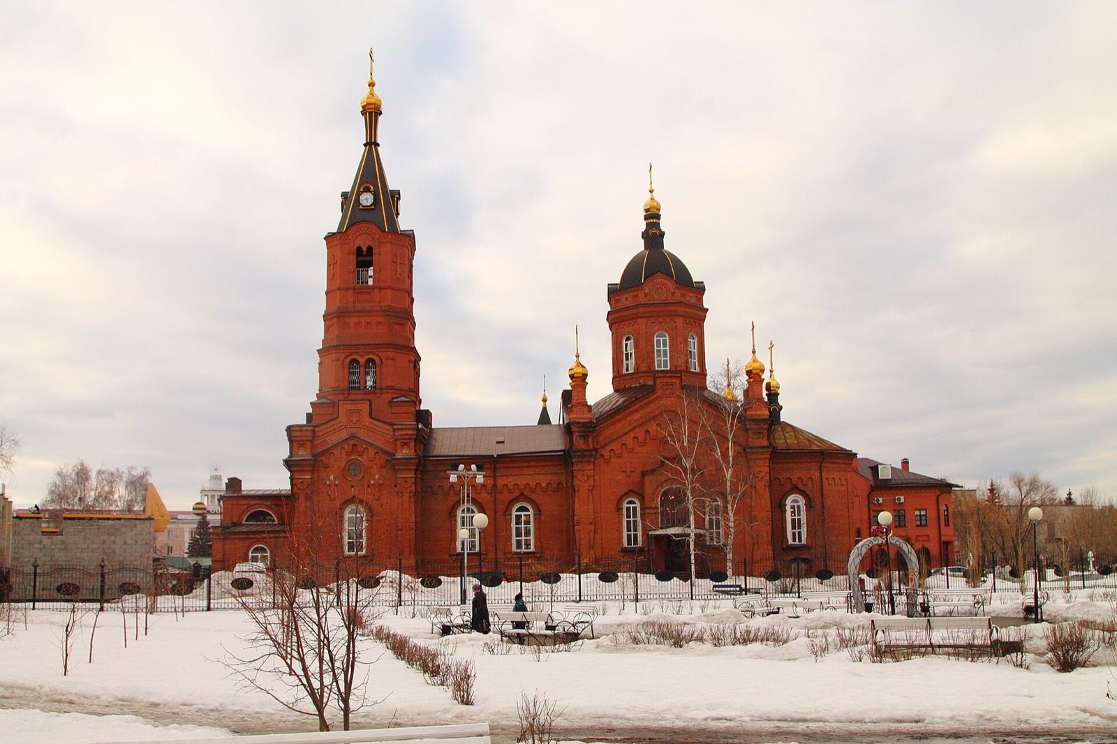 Александро-Невский собор из красного кирпича в Кургане зимой, вид из сквера со скамейками